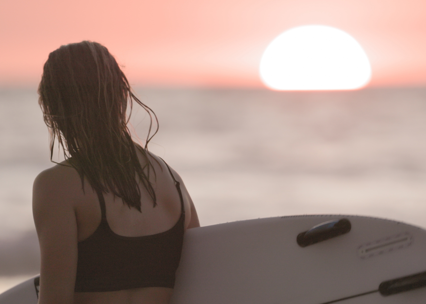 Costa Rica sunset surfer a pink Costa Rican sunset highlights a surfer holding her board